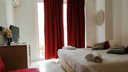 Et hotelværelse med en dobbeltseng, røde gardiner og et fjernsyn på en kommode. (AI-genereret tekst)