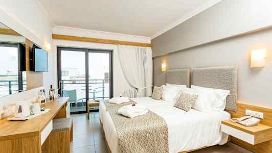 Moderne hotelværelse med dobbeltseng, skrivebord og balkon. (AI-genereret tekst)