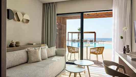 Lyse stuemøbler med udsigt over pool og hav. (AI-genereret tekst)