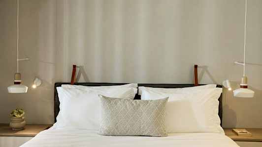 En seng med puder og oplyste lamper på begge sider. (AI-genereret tekst)