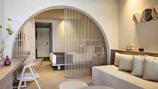 Moderne hotelværelse med siddeområde og skillevæg mod soveområdet. (AI-genereret tekst)