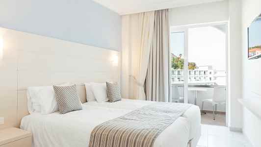 Hotelværelse med to enkeltsenge og altan. (AI-genereret tekst)