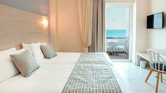 Hotelværelse med to senge, udsigt over havet fra balkonen. (AI-genereret tekst)