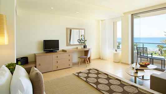 Lyst hotelværelse med havudsigt og balkon. (AI-genereret tekst)