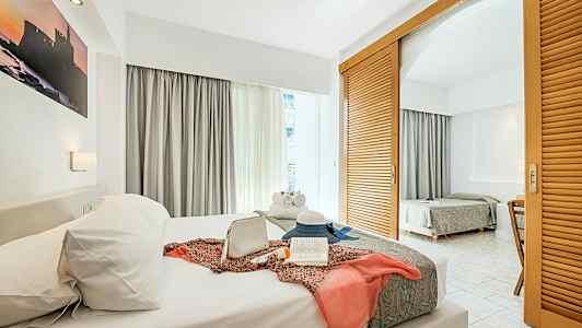 Et hotelværelse med to senge, dekoreret med personlige genstande på den forreste seng. (AI-genereret tekst)