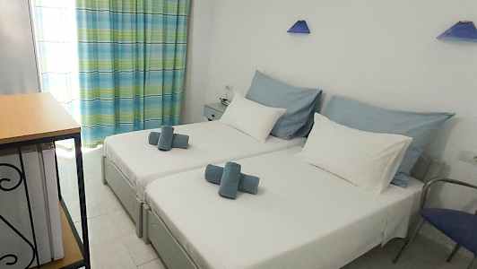 Billede af et hotelværelse med to enkeltsenge, hvidt sengetøj og blå dekoration. (AI-genereret tekst)