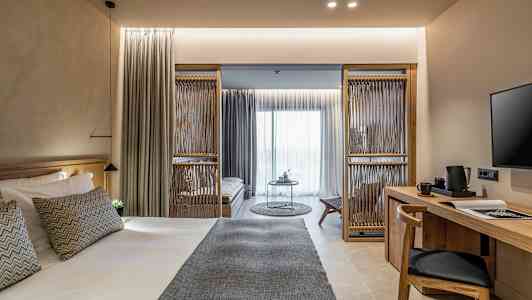 Et moderne hotelværelse med en stor seng, et skrivebord og en siddeområde. (AI-genereret tekst)