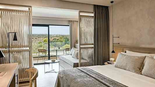 Hotelværelse med en dobbeltseng, siddeområde og en balkon med udsigt over natur. (AI-genereret tekst)