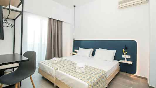 Moderne hotelværelse med to opredte enkeltsenge, skrivebord og stol samt vægmonteret aircondition. (AI-genereret tekst)