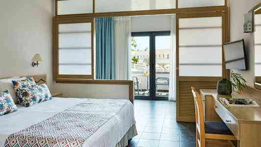 Hotelværelse med en seng, skrivebord og balkon. (AI-genereret tekst)