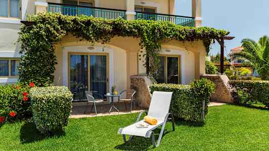 Billede af en solvogn med håndklæde og avis på græsplæne foran en terrasse. (AI-genereret tekst)