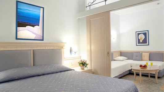 Et hotelværelse med to senge og en sofakrog, dekoreret med blomster og malerier. (AI-genereret tekst)