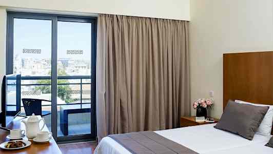 Et hotelværelse med stor seng, kaffekopper på et bord og en altan med udsigt. (AI-genereret tekst)