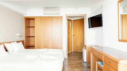 Hotelværelse med to enkeltsenge, garderobe, skrivebord og spejl. (AI-genereret tekst)