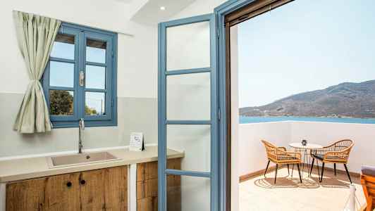 Et køkken med blå vinduer og en åben dør til balkonen med udsigt over havet. (AI-genereret tekst)