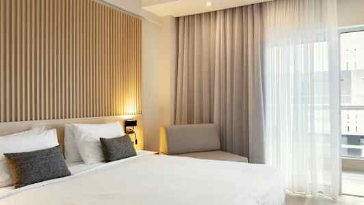 Soveværelse med en dobbeltseng, træpanel på væggen og store vinduer med lyse gardiner. (AI-genereret tekst)