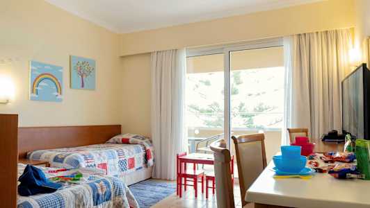 Et hotelværelse med to enkeltsenge og et bord med stole nær en altan. (AI-genereret tekst)