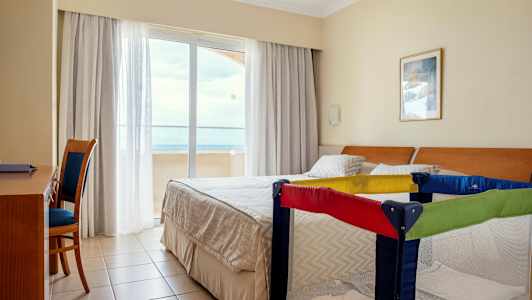 Hotelværelse med dobbeltseng og barneseng. (AI-genereret tekst)