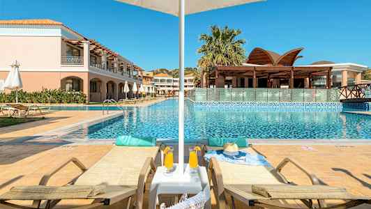 To liggestole ved en pool med parasol og en bygning i baggrunden. (AI-genereret tekst)