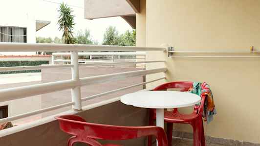 En altan med røde stole og et hvidt bord. (AI-genereret tekst)