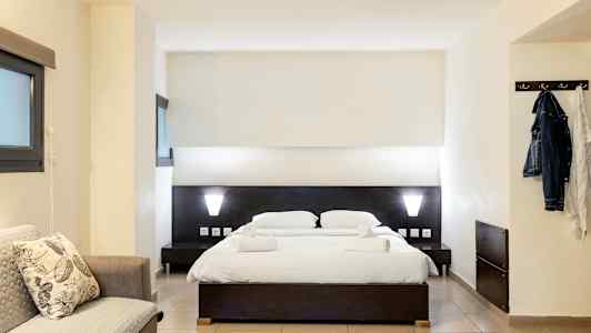 Et hotelværelse med en dobbeltseng, en sofa og en knagerække. (AI-genereret tekst)