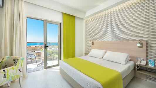 Et hotelværelse med en seng, grønt sengetæppe, lyse møbler og en altan med havudsigt. (AI-genereret tekst)