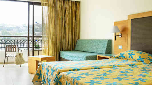 Et hotelværelse med en seng, sofa og balkon. (AI-genereret tekst)