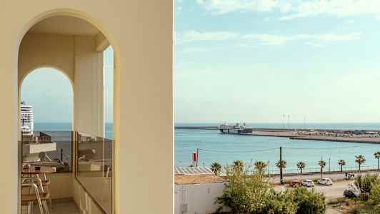 Udsigt mod havet med et krydstogtskib og en færge ved havnen, set gennem en buet åbning. (AI-genereret tekst)