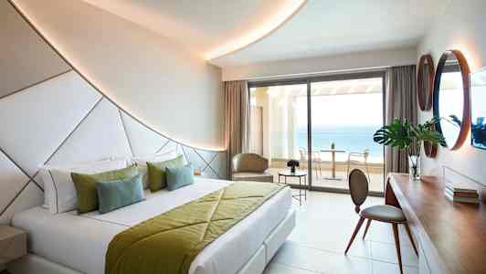 Moderne hotelværelse med dobbeltseng og havudsigt fra altanen. (AI-genereret tekst)