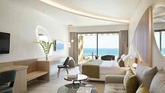 Et hotelværelse med moderne indretning og udsigt over havet. (AI-genereret tekst)