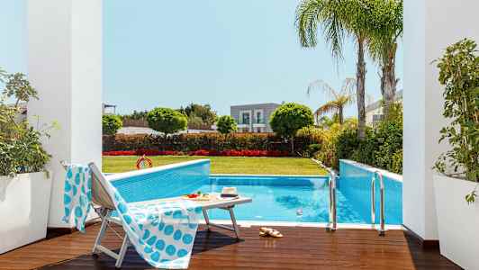 Udendørs pool omgivet af grønne områder og liggestole. (AI-genereret tekst)