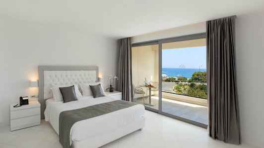 Et soveværelse med en dobbeltseng og udsigt over havet gennem store vinduer. (AI-genereret tekst)