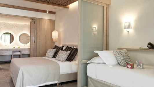 Et moderne hotelværelse med to senge, dekorativ belysning og et synligt badeområde med to spejle. (AI-genereret tekst)