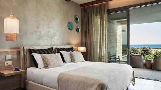 Et hotelværelse med en seng og udsigt til havet. (AI-genereret tekst)