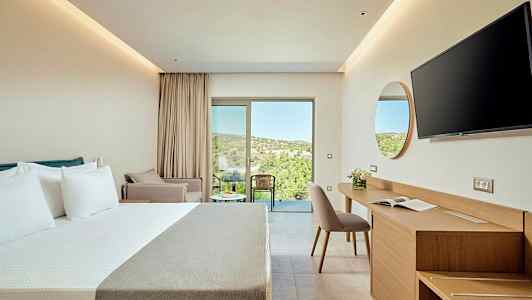 Et moderne hotelværelse med dobbeltseng, skrivebord og stol samt en altan med udsigt over frodigt terræn. (AI-genereret tekst)