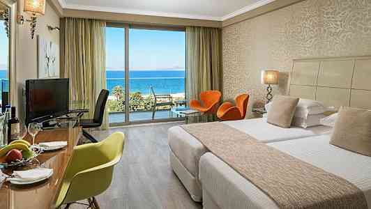 Hotelværelse med senge, siddepladser og udsigt over havet. (AI-genereret tekst)