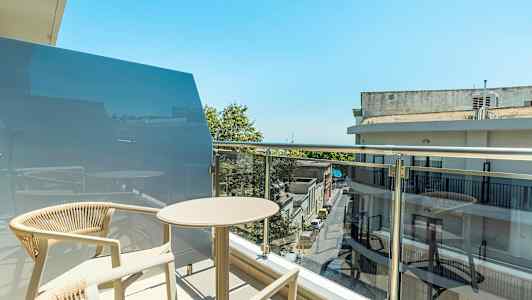 En altan med bord og stole i et bymiljø. (AI-genereret tekst)