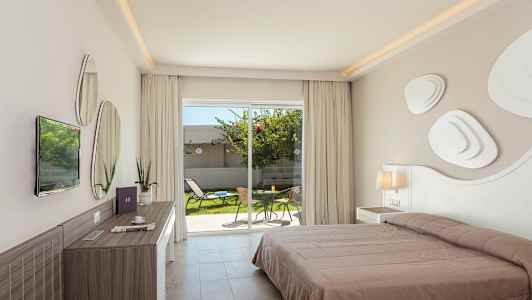 Et hotelværelse med en dobbeltseng, skrivebord og udsigt til et privat haveområde med møbler gennem glasdøre. (AI-genereret tekst)