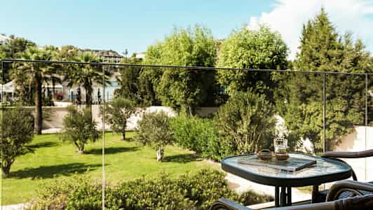 En altan med et bord og stole samt udsigt til en grøn have. (AI-genereret tekst)