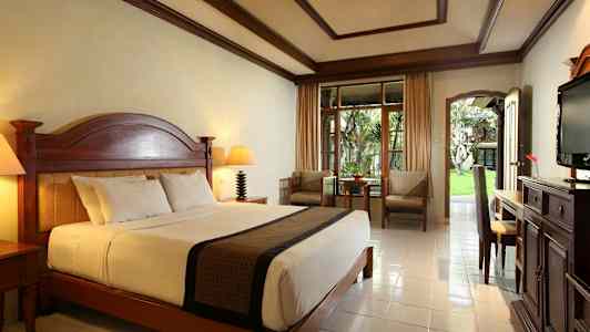 Et velindrettet hotelværelse med en stor seng og en udendørs terrasse. (AI-genereret tekst)