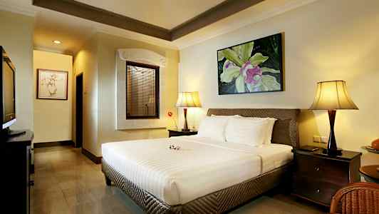 Et soveværelse med en stor seng, to natbordslamper og et dekorativt billede på væggen. (AI-genereret tekst)