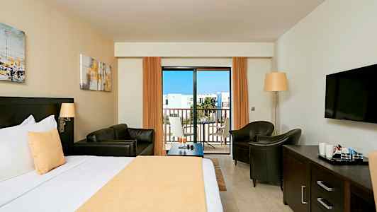 Hotelværelse med en seng, siddeområde, tv og altan. (AI-genereret tekst)