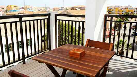 Udsigt fra en altan med et træbord og stole. (AI-genereret tekst)