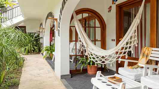 En terrasse med hvide stole, en hængekøje og grønne planter. (AI-genereret tekst)