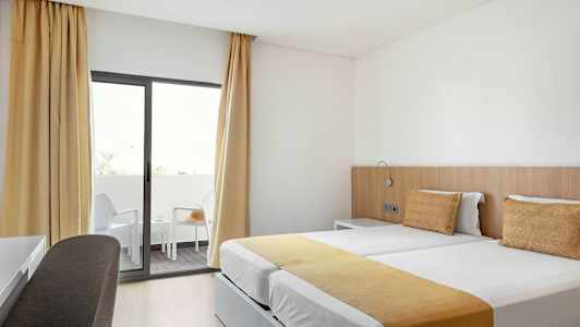 Hotelværelse med to enkeltsenge og altan. (AI-genereret tekst)