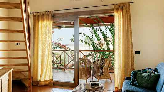 Interiør med trappe, sofahjørne og terrasse med siddepladser og grønne planter. (AI-genereret tekst)