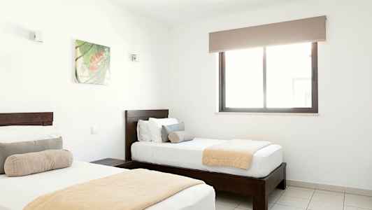 To enkeltsenge i et lyst soveværelse med et vindue og en vægdekoration. (AI-genereret tekst)