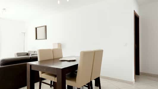 En moderne indrettet stue med spisebord og stole i forgrunden. (AI-genereret tekst)