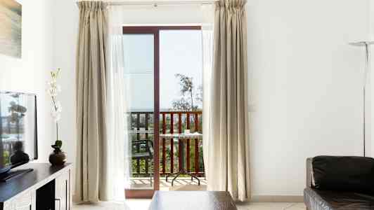 Et værelse med siddeområde, et tv og en altan med udsigt. (AI-genereret tekst)