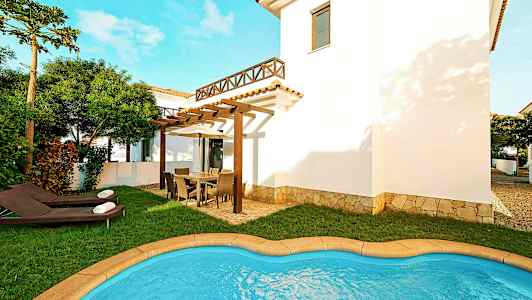 Billede af en villa med en lille pool, græsplæne og havemøbler på en rummelig terrasse. (AI-genereret tekst)